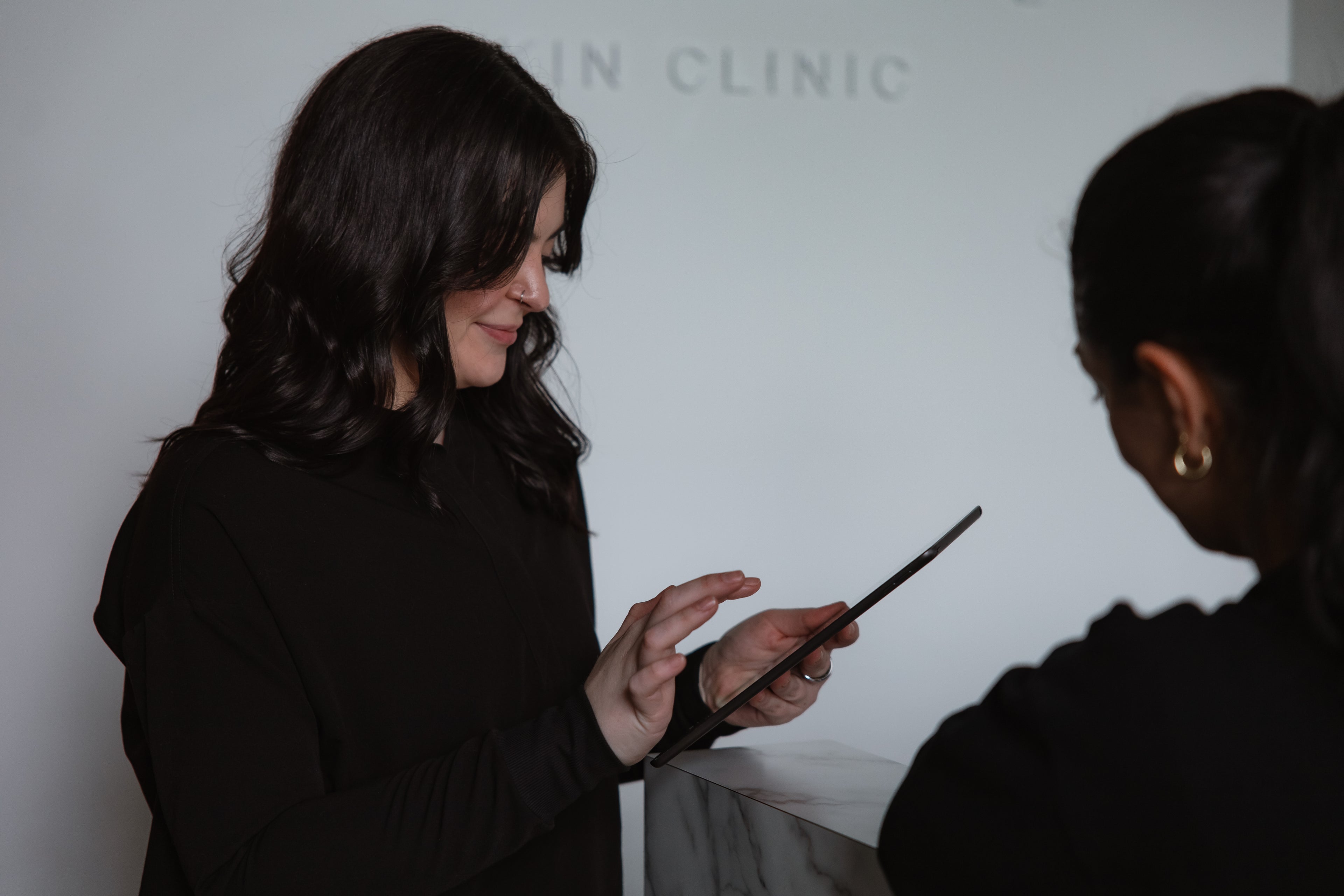 Clinician and client reviewing information on a tablet during a consultation at KOZA Skin Clinic, Port Coquitlam, Tri-Cities BC.