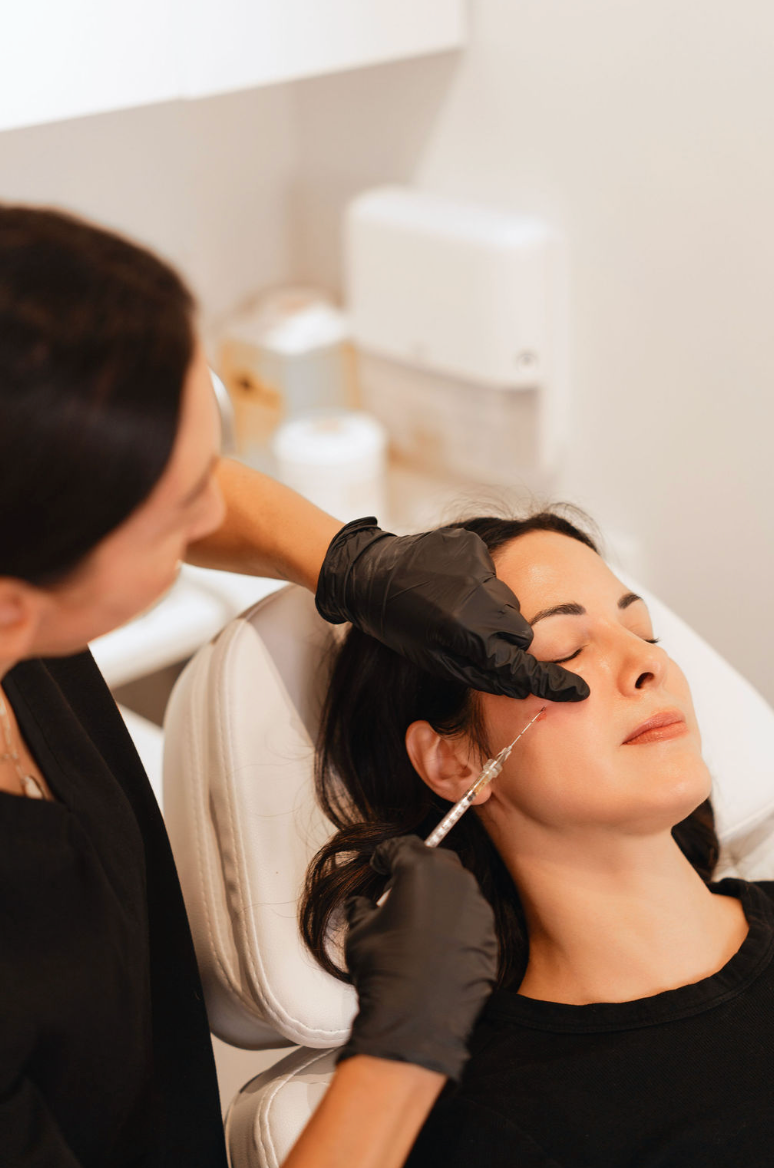 Clinician administering a dermal filler injection to a client's cheek during a facial treatment at KOZA Skin Clinic, Port Coquitlam, Tri-Cities BC